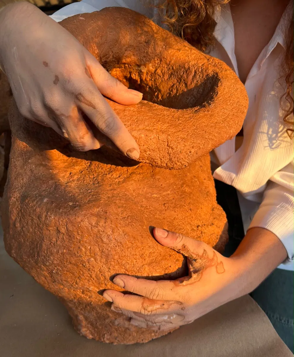 Mãos da artista construindo uma escultura